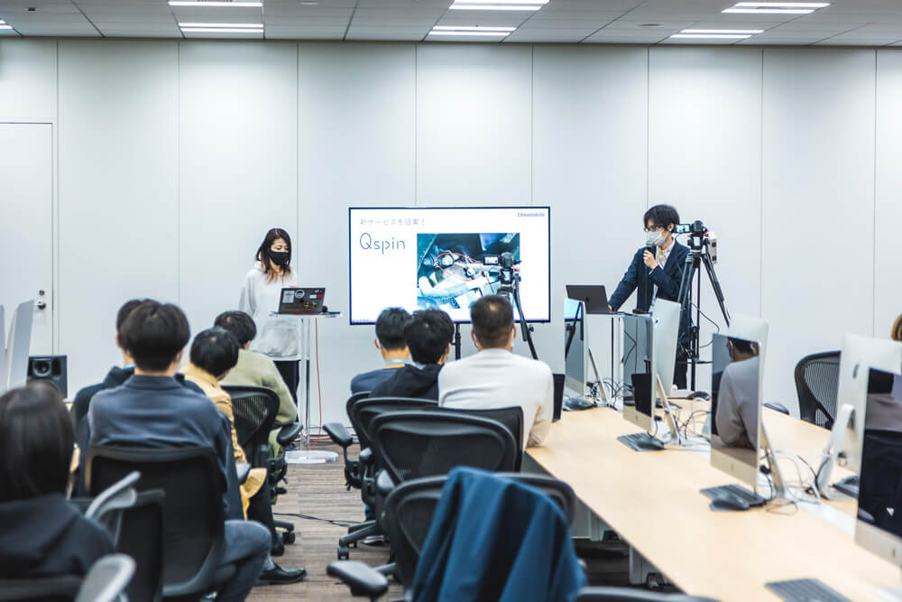 42 Tokyo 開会式で、課題を説明するドリーム・アーツの矢田(ステージ右)