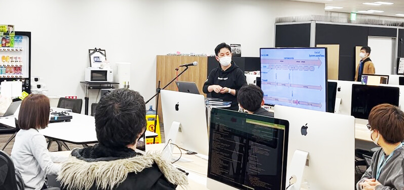 42 Tokyo 開会式で、課題を説明するドリーム・アーツの矢田(ステージ右)